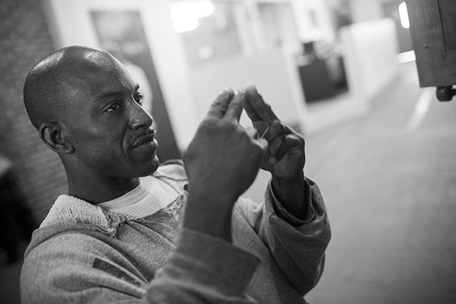Black and white photo of a prisoner signing to a videophone.