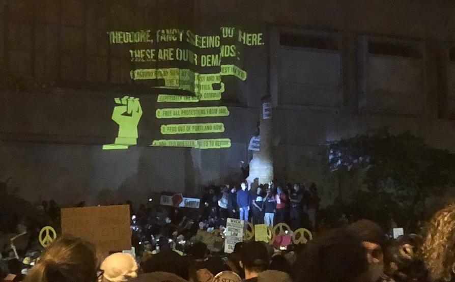 Protestor Demands projected onto federal building