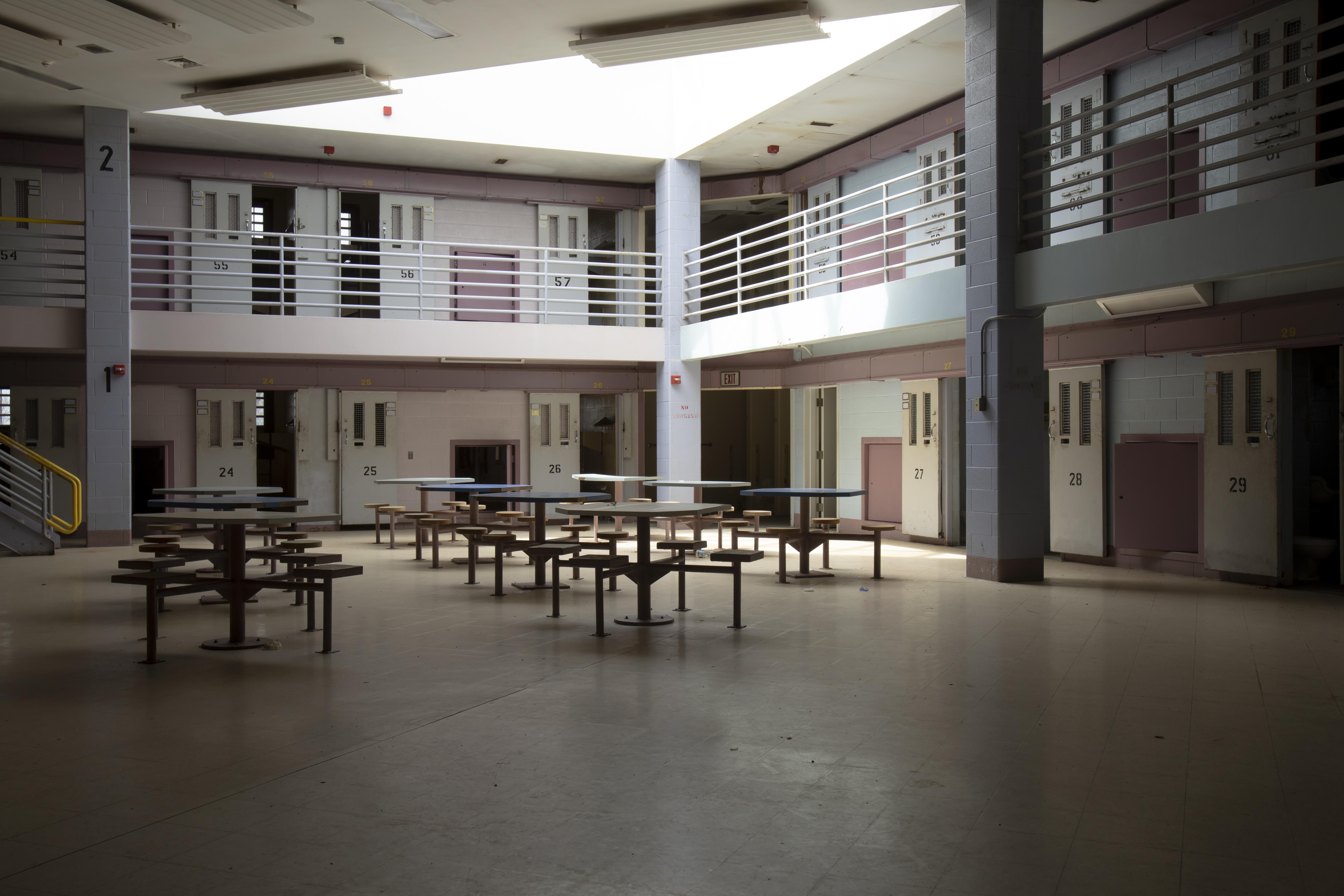 Interior of an empty cell block in jail with large dayspace and closed cells.