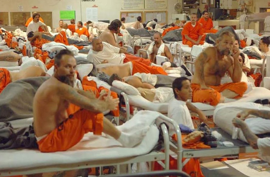 Crowded prison gym with many bunkbeds